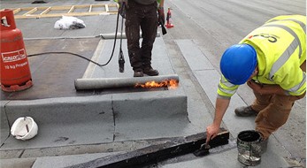 Roofer torching a felt membrane on a flat roof